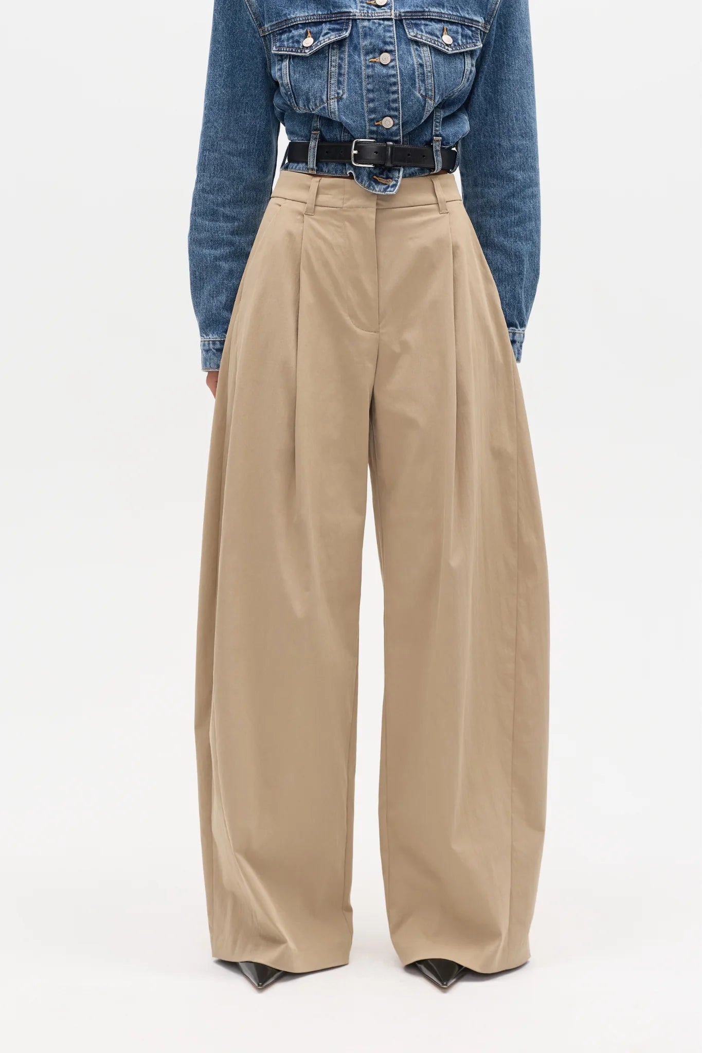 Person wearing beige wide-leg pants with a blue denim jacket on a white background