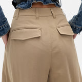 Person wearing beige pants and a blue denim shirt on a white background