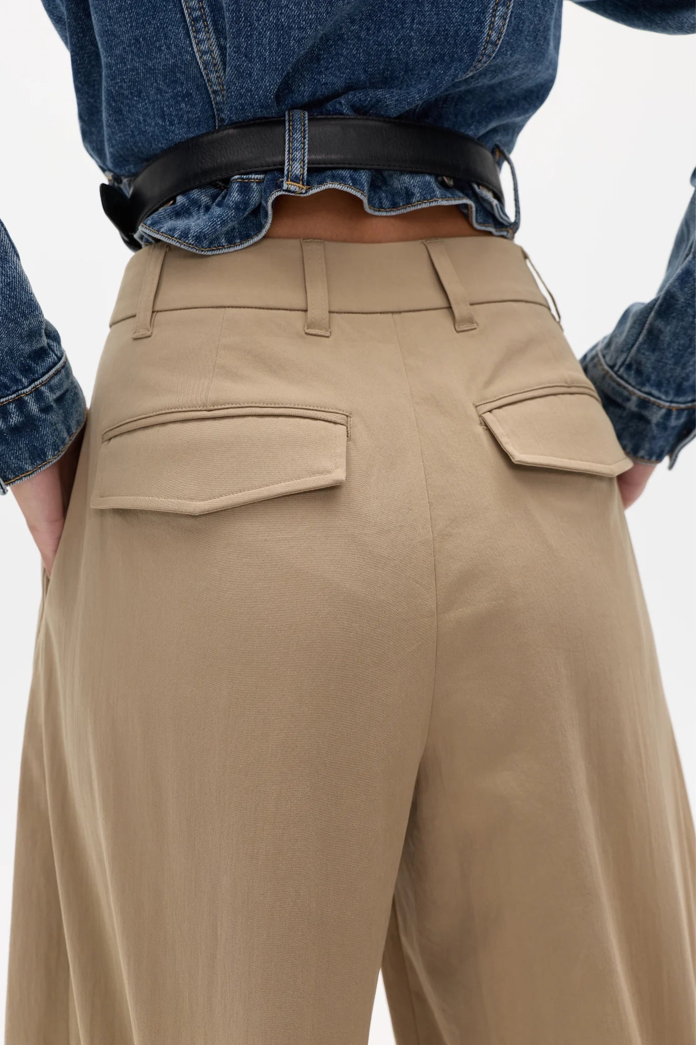 Person wearing beige pants and a blue denim shirt on a white background