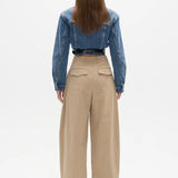 Person wearing a blue denim jacket and beige pants on a white background