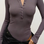 Purple long-sleeve top worn by a person on a plain background