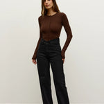 Woman wearing a brown top and black pants against a white background