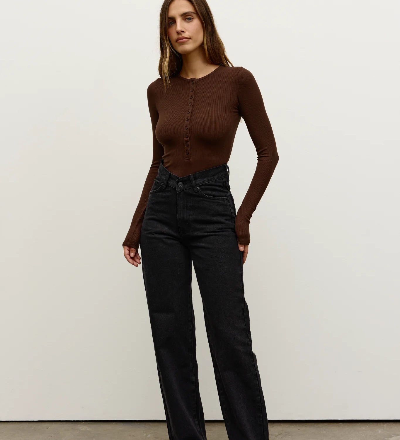 Woman wearing a brown top and black pants against a white background