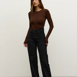 Woman wearing a brown top and black pants against a white background