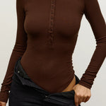 Brown long-sleeve top worn by a person on a plain background