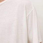 Close-up of a person wearing an oversized white short-sleeve crewneck t-shirt against a plain light background.