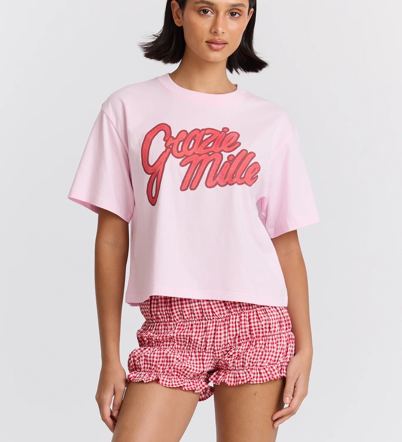Woman wearing a pink 'Gottie Miller' t-shirt and red checkered shorts on a white background