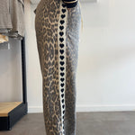 Person wearing leopard print pants with heart pattern on a plain background