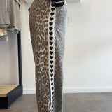 Person wearing leopard print pants with heart pattern on a plain background
