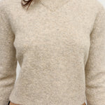 Beige sweater worn by a person on a plain background