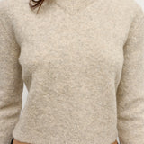 Beige sweater worn by a person on a plain background