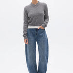 Person wearing a gray sweater and blue jeans on a white background