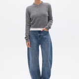 Person wearing a gray sweater and blue jeans on a white background