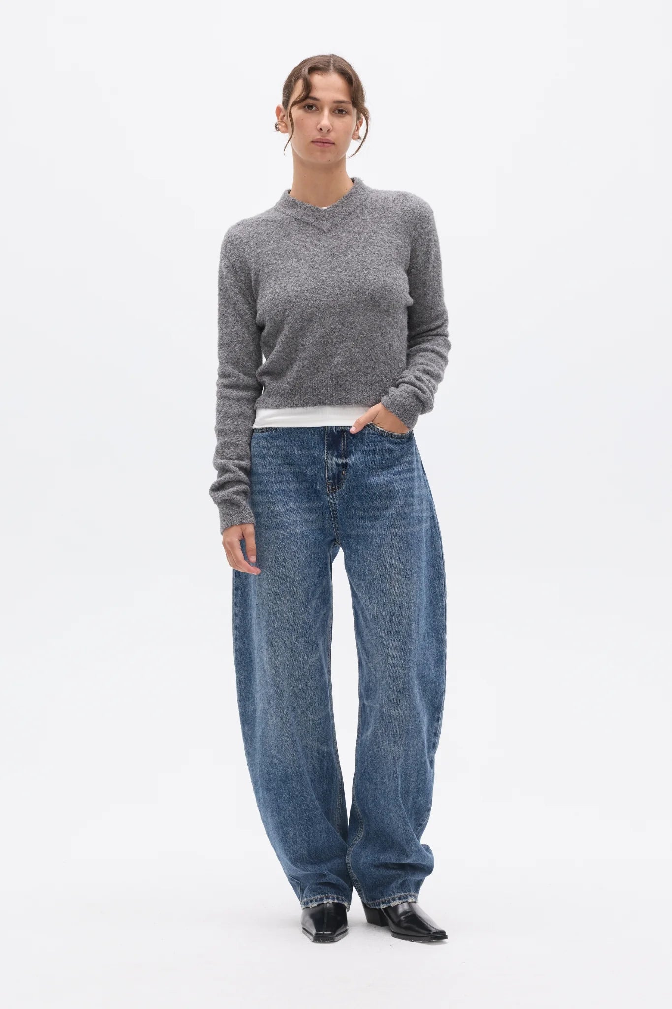 Person wearing a gray sweater and blue jeans on a white background