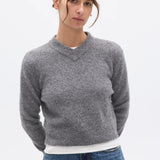 Woman wearing a gray sweater and blue jeans on a white background
