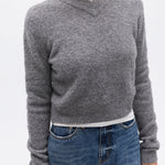 Person wearing a gray sweater and blue jeans on a white background