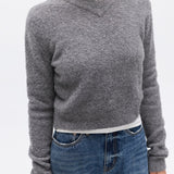 Person wearing a gray sweater and blue jeans on a white background