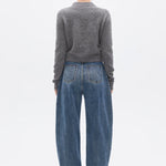 Person wearing a gray sweater and blue jeans on a white background
