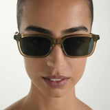 Person wearing Sage sunglasses with a neutral background