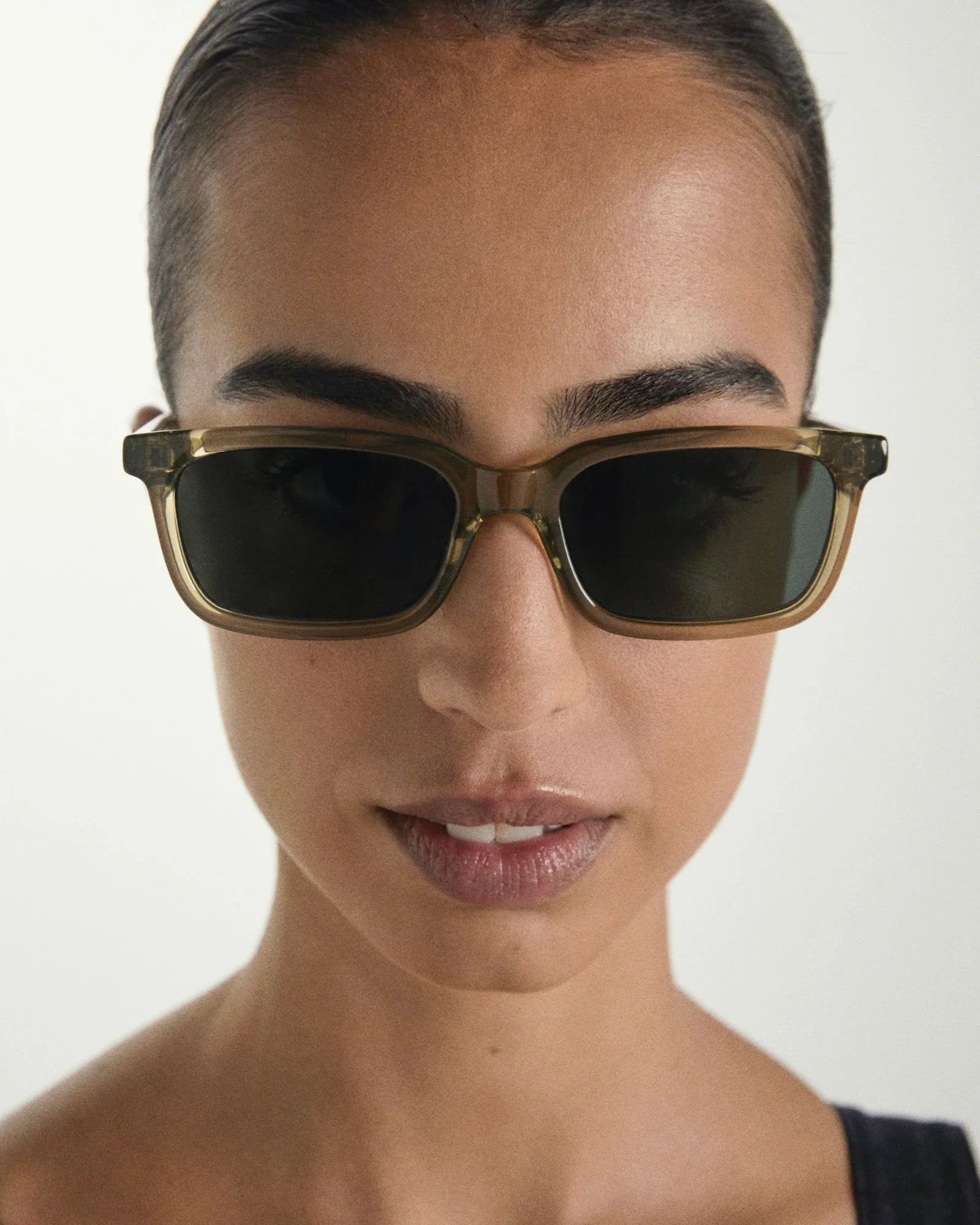 Person wearing Sage sunglasses with a neutral background