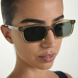 Close-up of a person wearing Sage framed sunglasses with a neutral background