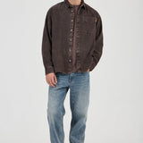 Man wearing a brown button-up shirt and blue jeans on a white background