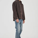 Man wearing a brown shirt and blue jeans on a white background