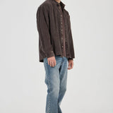 Man wearing a brown shirt and blue jeans on a white background