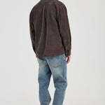 Man wearing a brown shirt and blue jeans on a white background