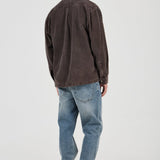 Man wearing a brown shirt and blue jeans on a white background
