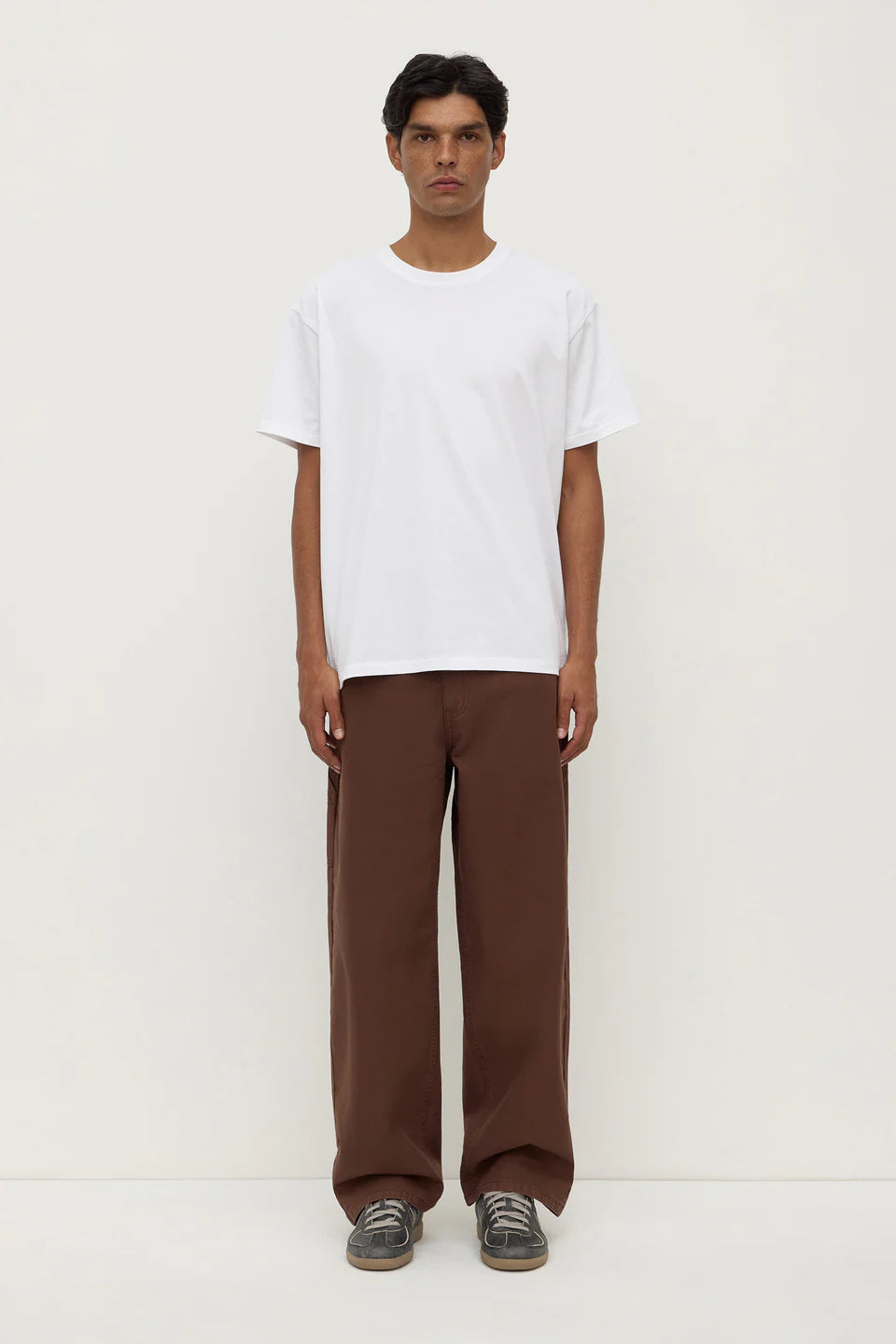 Person wearing a white t-shirt and brown pants on a white background