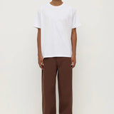 Person wearing a white t-shirt and brown pants on a white background
