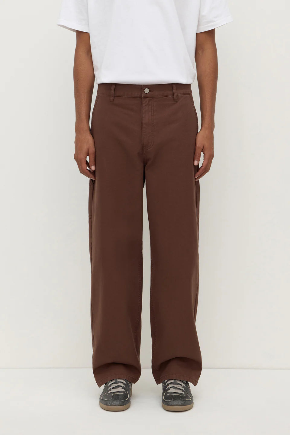 Person wearing brown pants and a white shirt on a white background