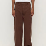 Person wearing brown pants and a white shirt on a white background