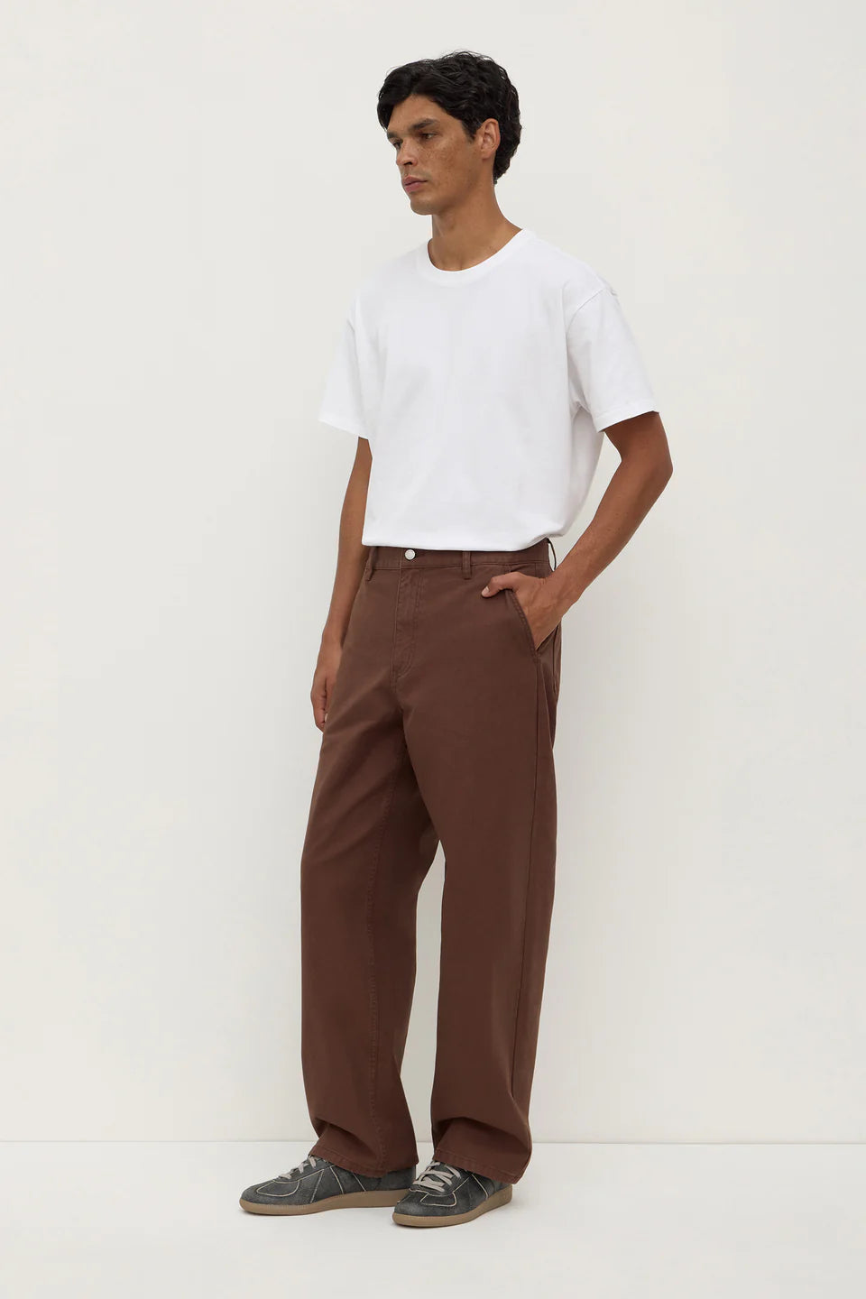 Man wearing a white t-shirt and brown pants on a white background