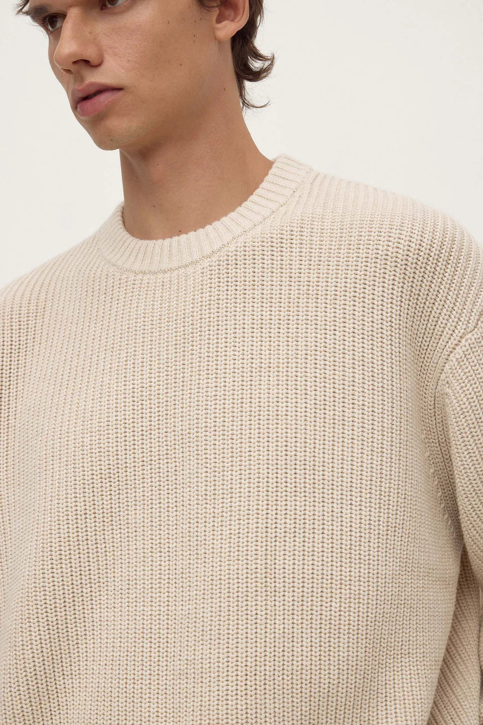 Beige knitted sweater worn by a person on a white background