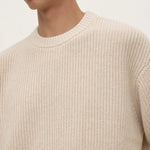 Beige knitted sweater worn by a person on a white background