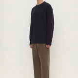 Man wearing a navy sweater and brown pants on a white background