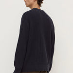 Person wearing a dark blue sweater and brown pants on a white background