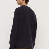 Person wearing a dark blue sweater and brown pants on a white background