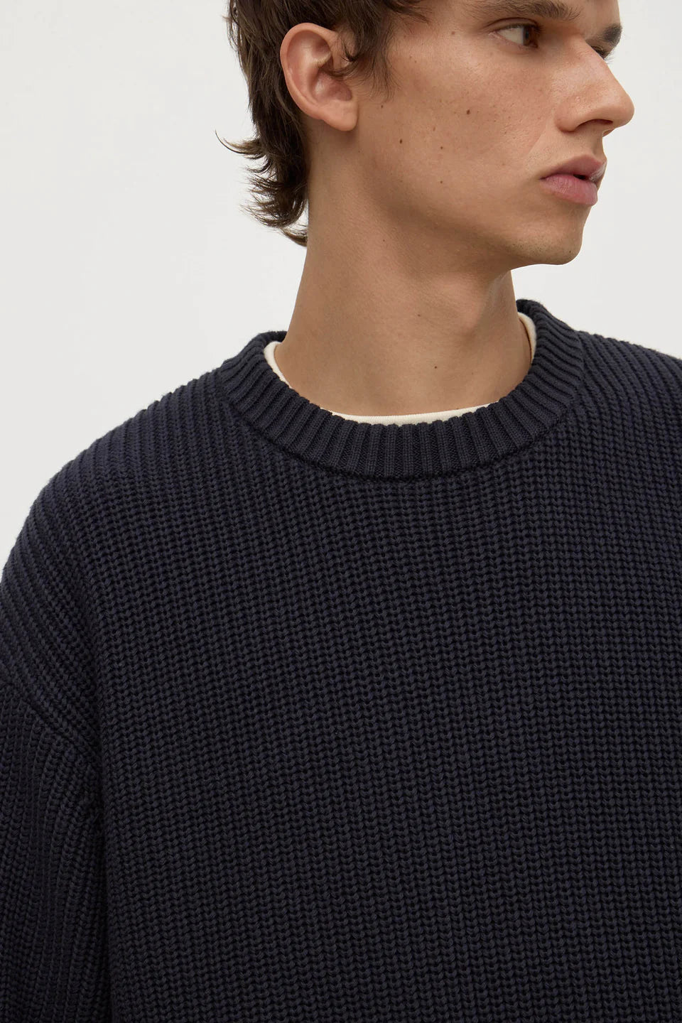Man wearing a dark blue textured sweater against a plain background