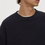 Man wearing a dark blue textured sweater against a plain background