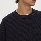 Man wearing a dark blue textured sweater against a plain background