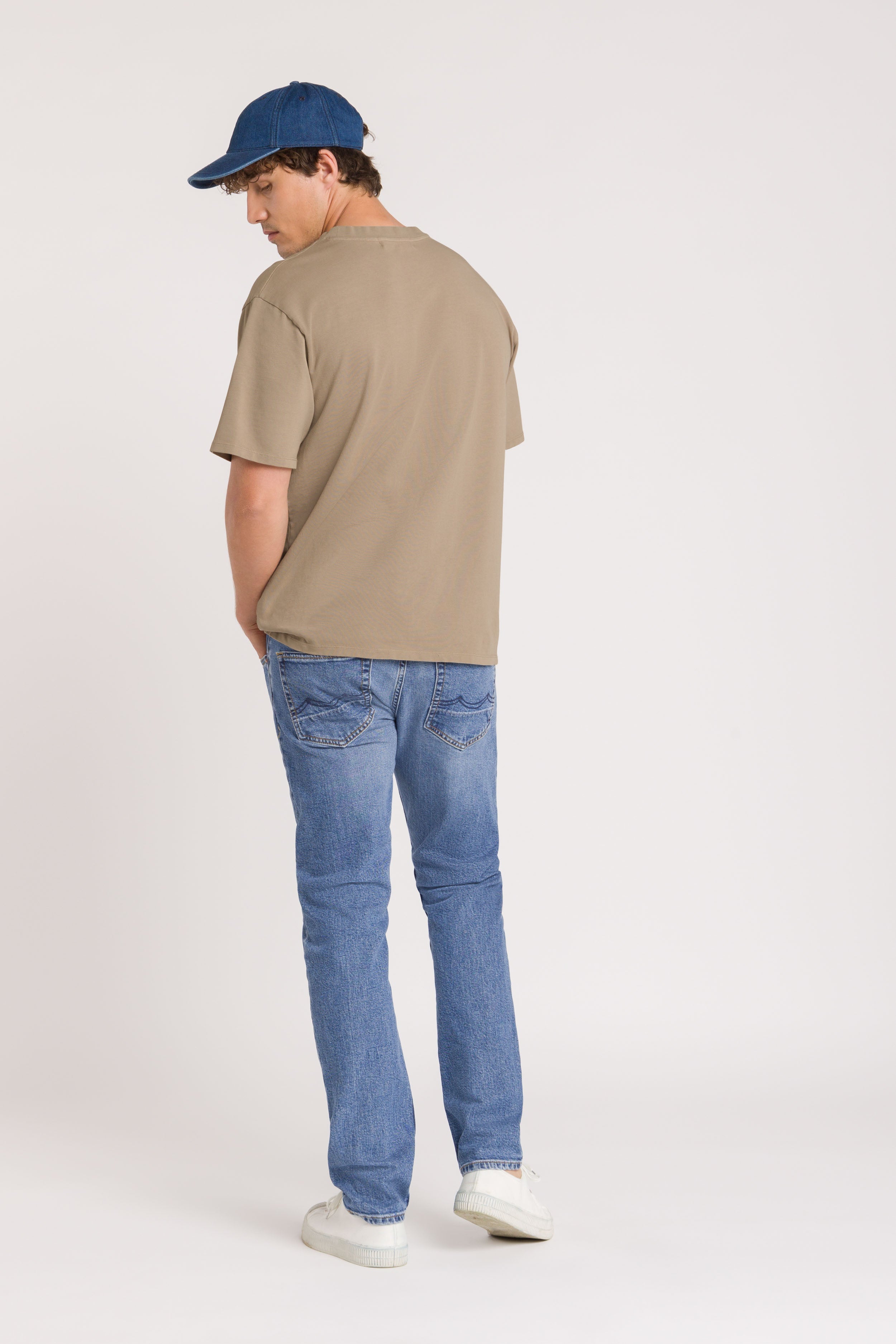 Man wearing Blue Jeans Beige top and denim cap on white Background