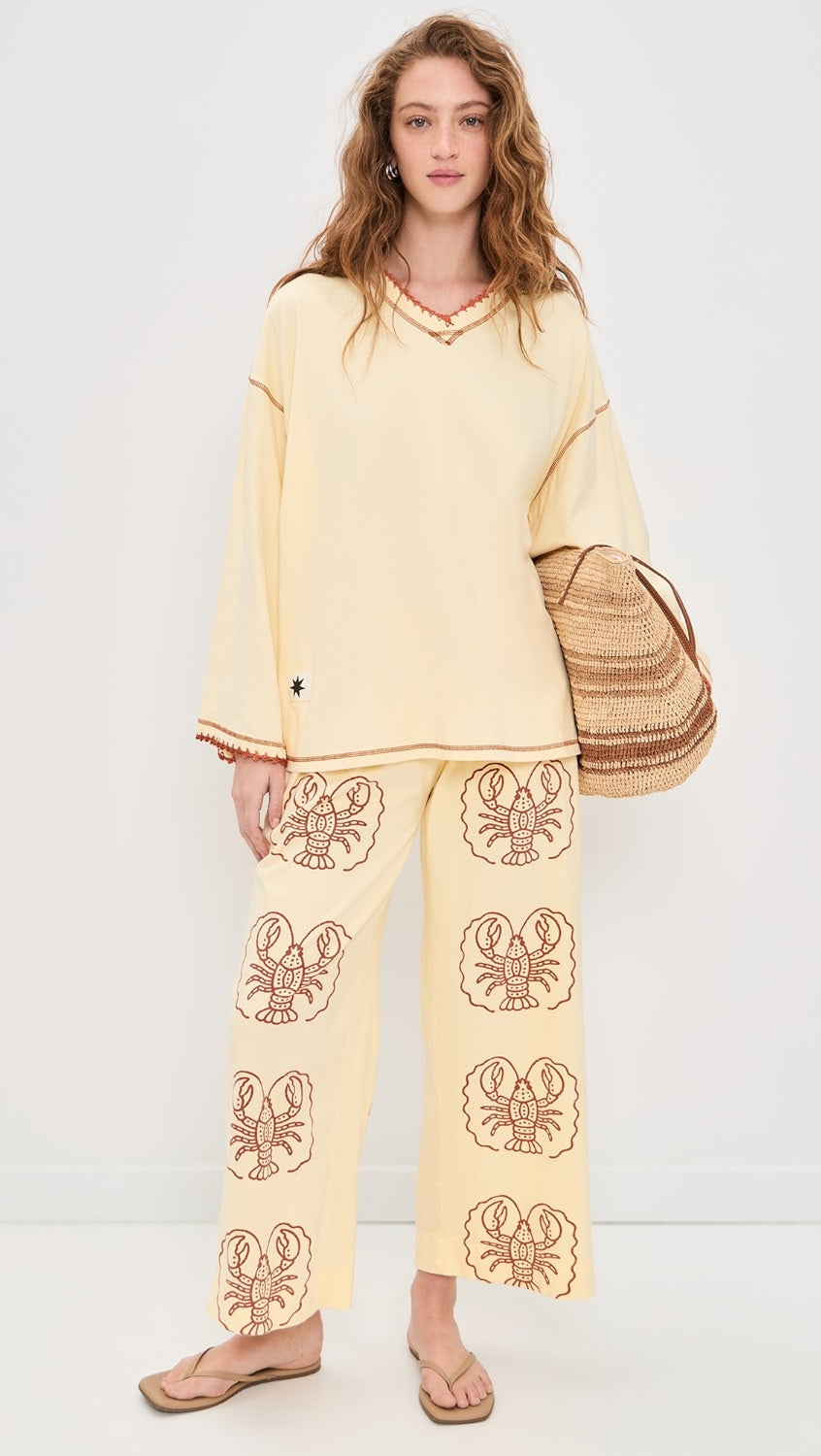 Women wearing Yellow pants with Lobster print and Yellow top in front of white background