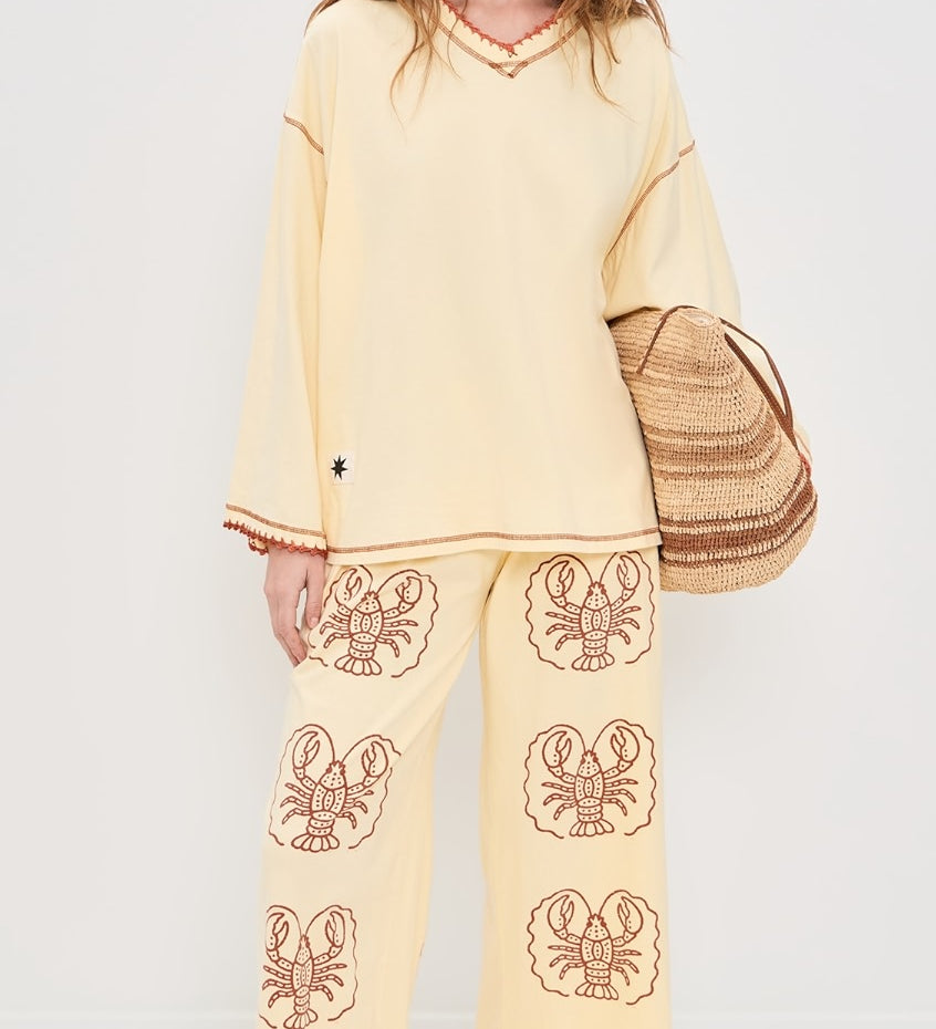 Women wearing Yellow pants with Lobster print and Yellow top in front of white background