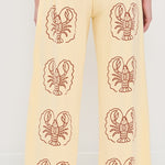 Yellow pants with lobster patterns worn by a person on a white background