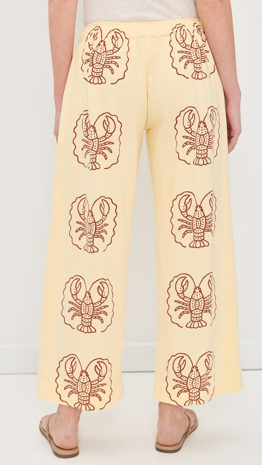 Yellow pants with lobster patterns worn by a person on a white background