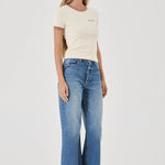 Woman wearing a cream t-shirt and blue jeans on a white background
