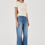 Woman wearing a cream t-shirt and blue jeans on a white background